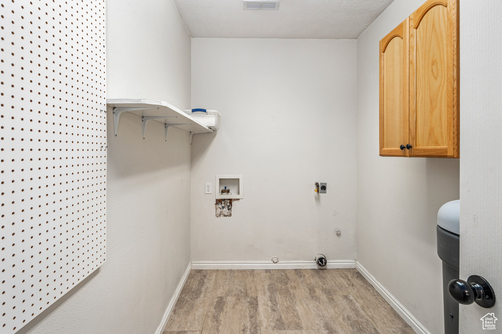 Laundry room featuring washer hookup, light wood-style flooring, cabinet space, hookup for an electric dryer, and baseboards