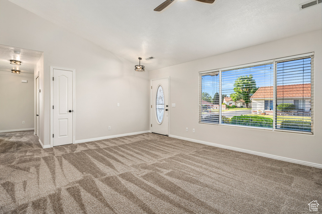 Carpeted spare room featuring a ceiling fan, lofted ceiling, and baseboards