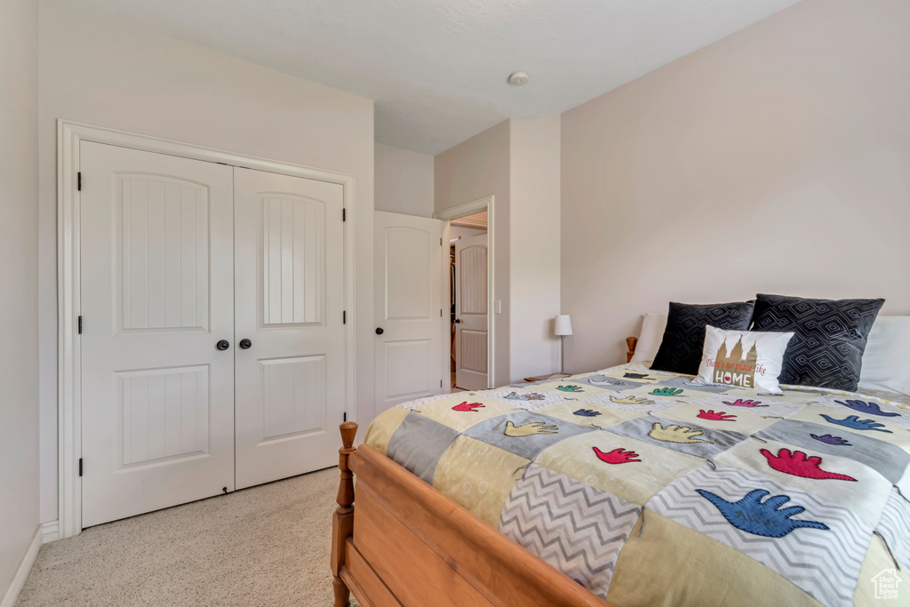 Bedroom featuring light colored carpet, a closet, and baseboards