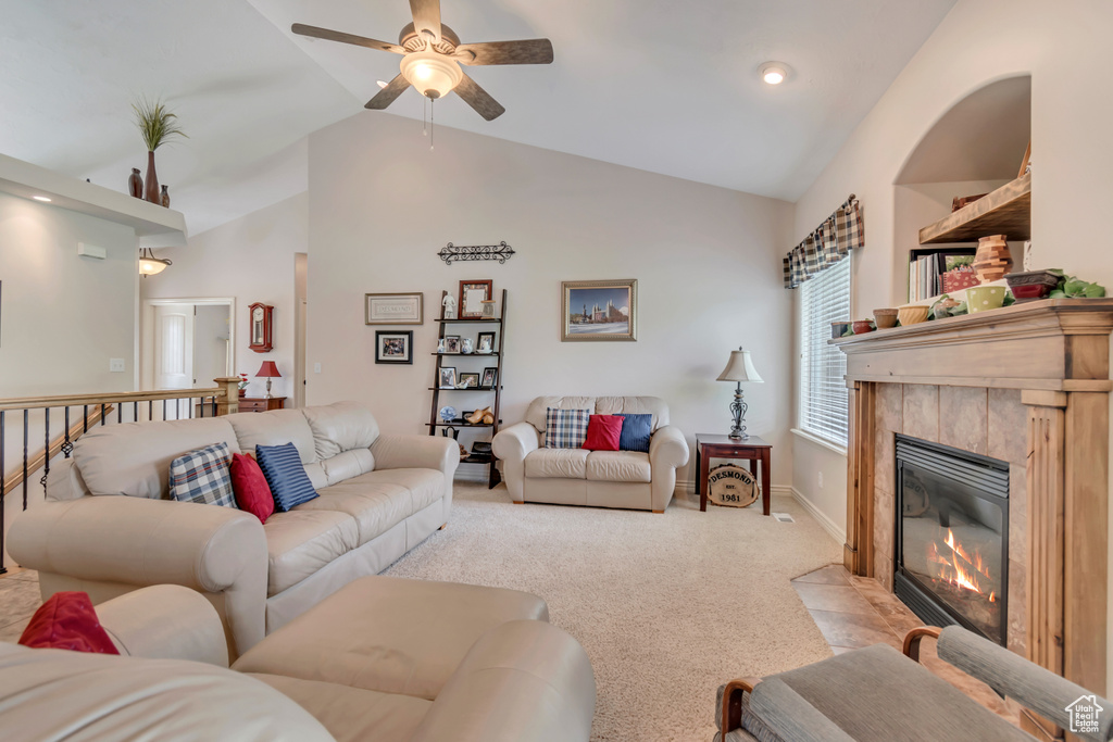 Living room with ceiling fan, light colored carpet, a tile fireplace, high vaulted ceiling, and baseboards