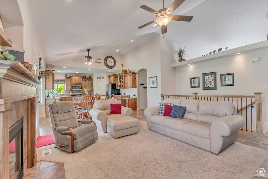 Living area featuring ceiling fan, a fireplace, arched walkways, recessed lighting, and high vaulted ceiling