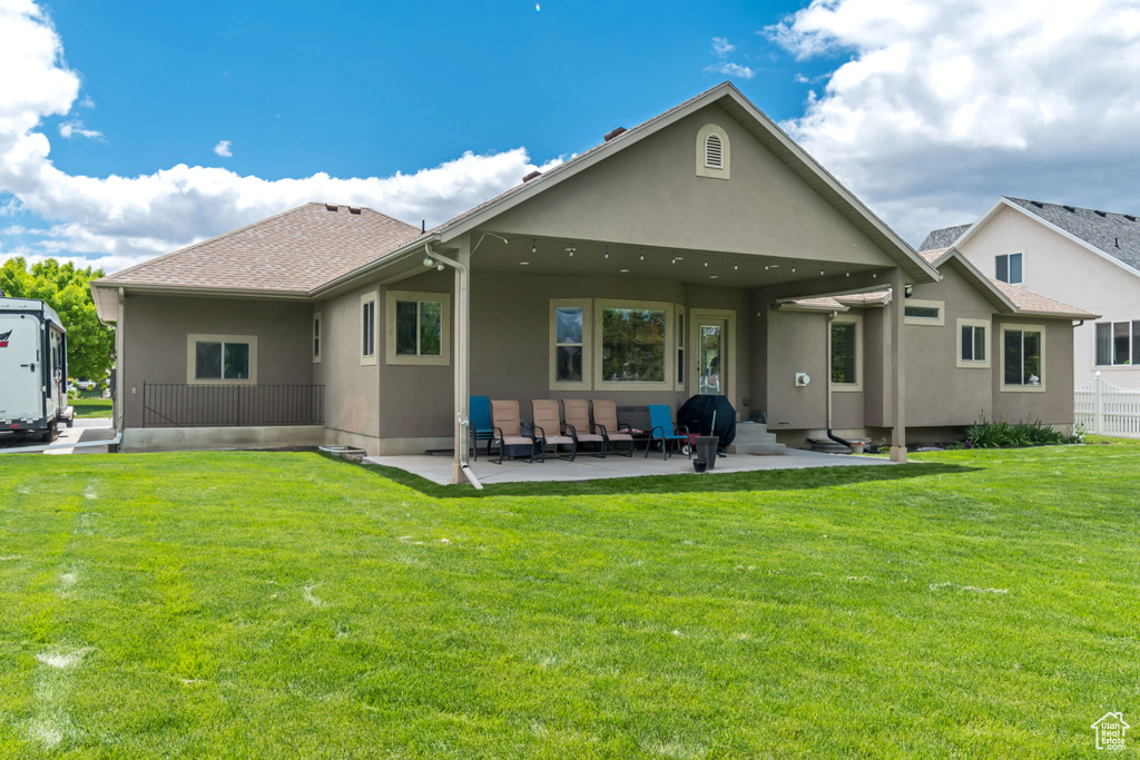 Rear view of house with a patio area, stucco siding, and a lawn