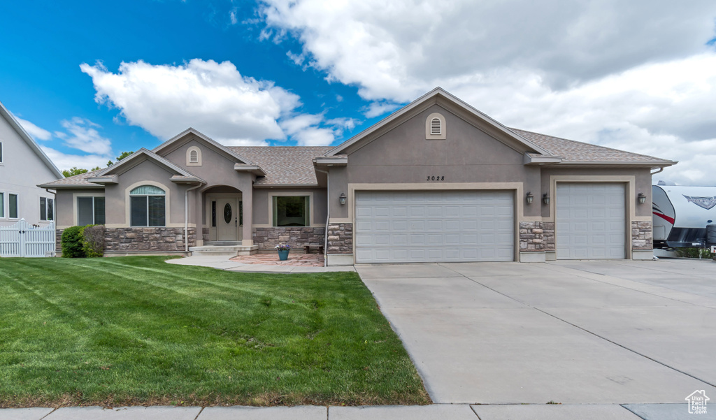 View of front of property with stucco siding, stone siding, a garage, and driveway
