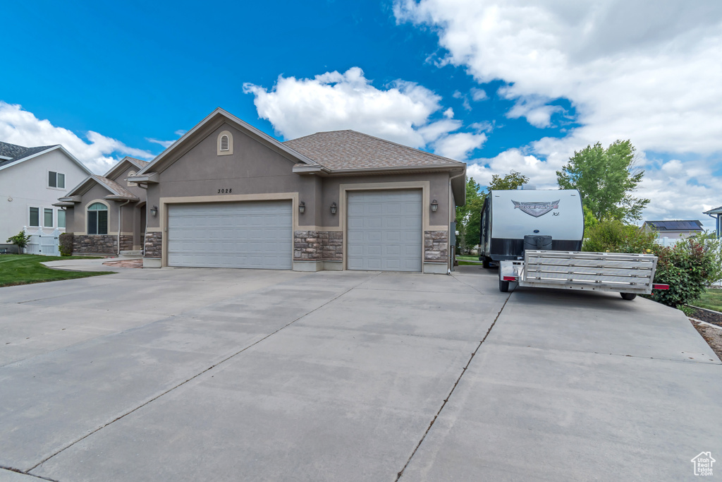 View of front facade with stucco siding, stone siding, an attached garage, and concrete driveway