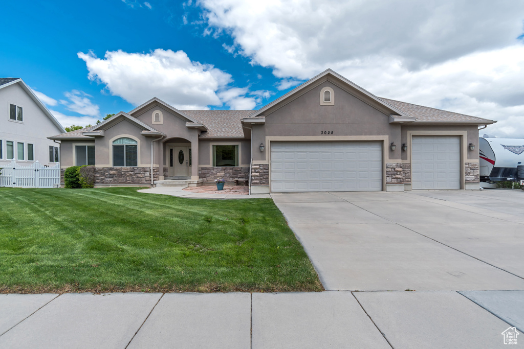 View of front facade featuring stucco siding, stone siding, and an attached garage