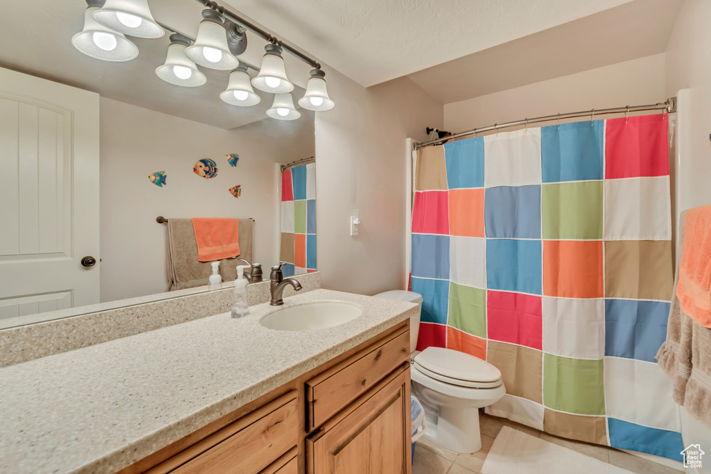 Bathroom with toilet, vanity, tile patterned floors, and a shower with curtain