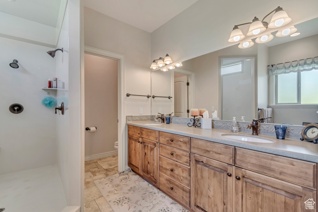 Bathroom featuring double vanity, a walk in shower, and toilet
