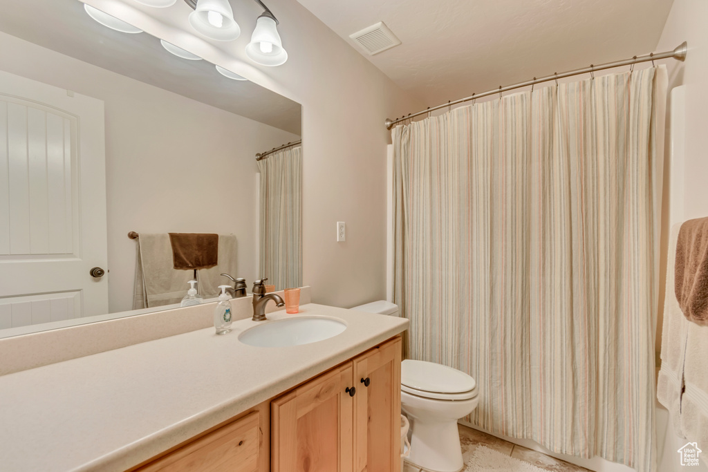 Bathroom with toilet, vanity, and a shower with curtain