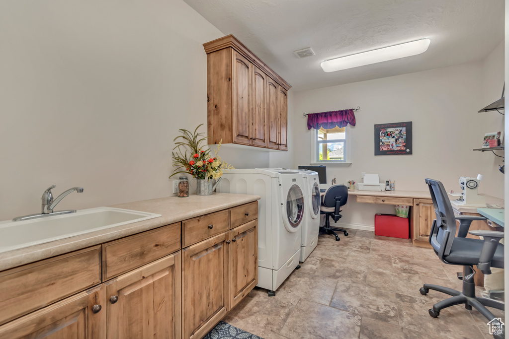 Washroom with cabinet space, independent washer and dryer, a desk, light stone finish flooring, and baseboards