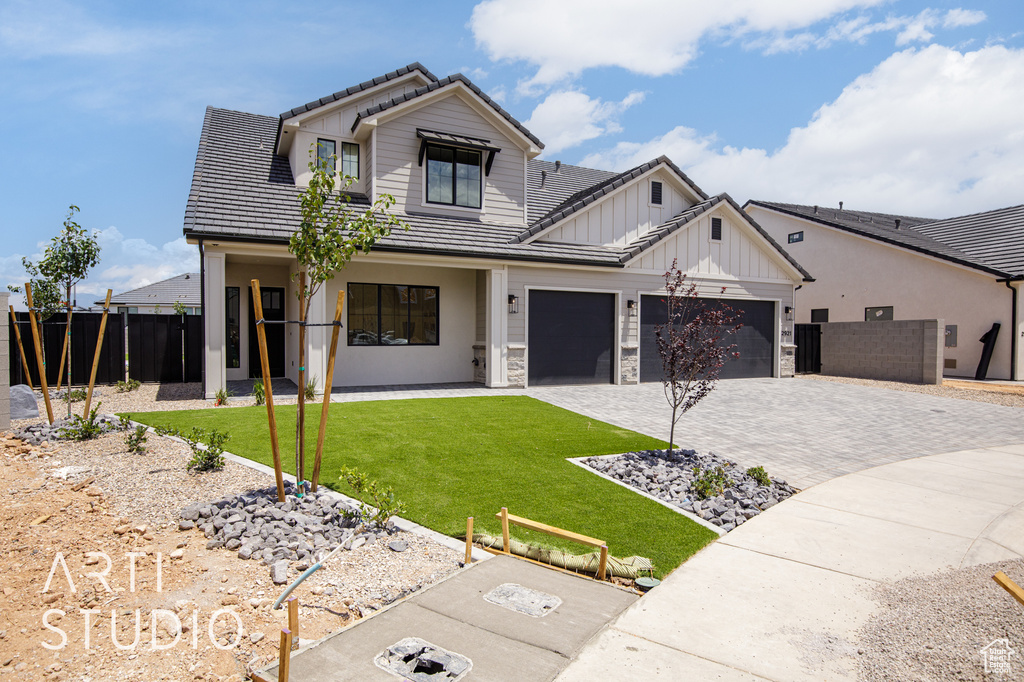 Modern farmhouse style home with a tiled roof, decorative driveway, an attached garage, and board and batten siding