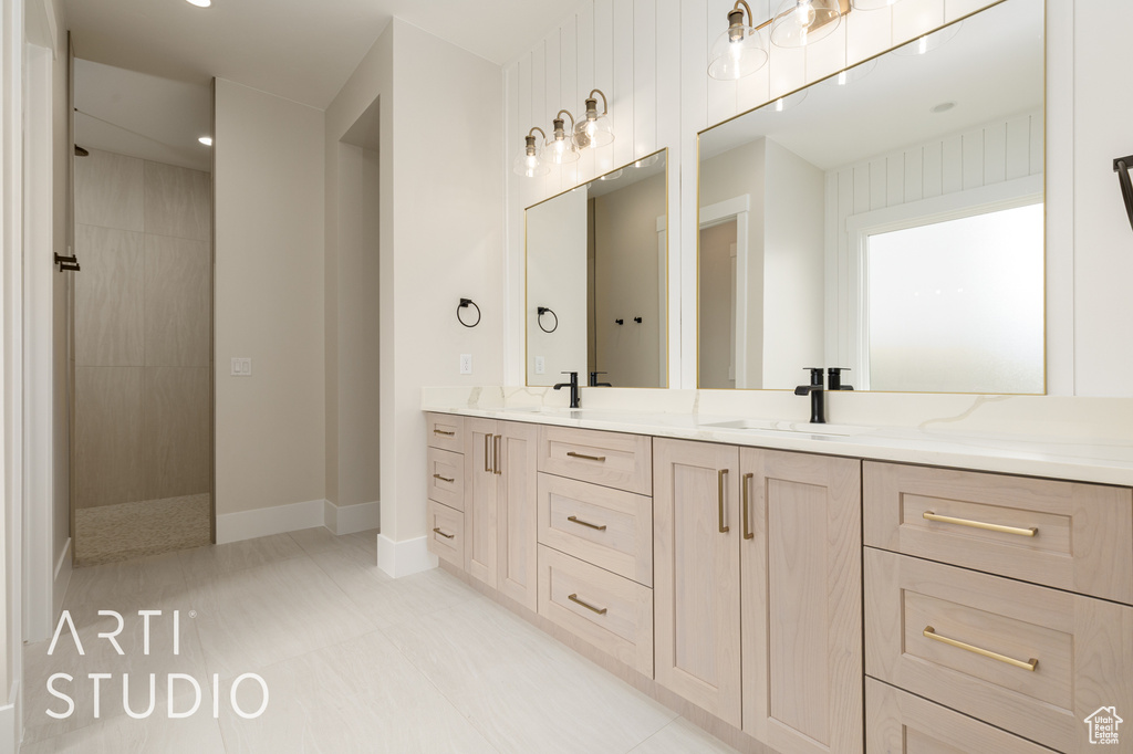 Full bath featuring double vanity, walk in shower, and baseboards