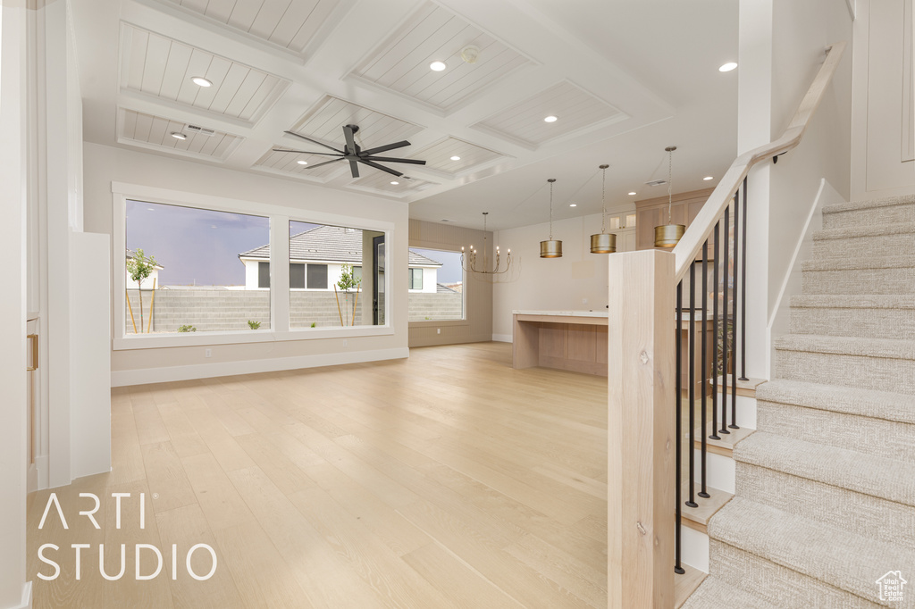 Unfurnished living room featuring coffered ceiling, light wood-type flooring, recessed lighting, stairway, and beam ceiling