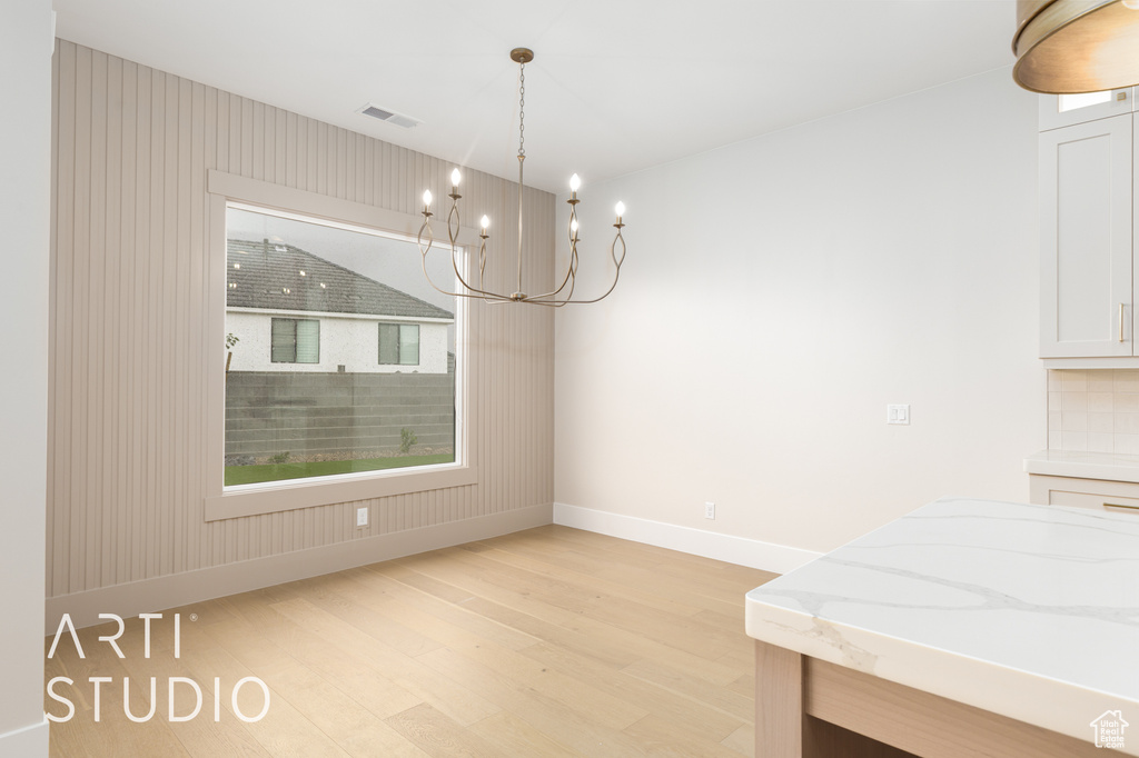 Dining space with light wood finished floors, baseboards, and a chandelier