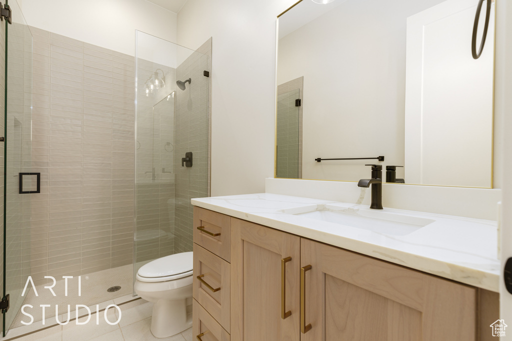 Bathroom featuring toilet, vanity, a shower stall, and tile patterned flooring