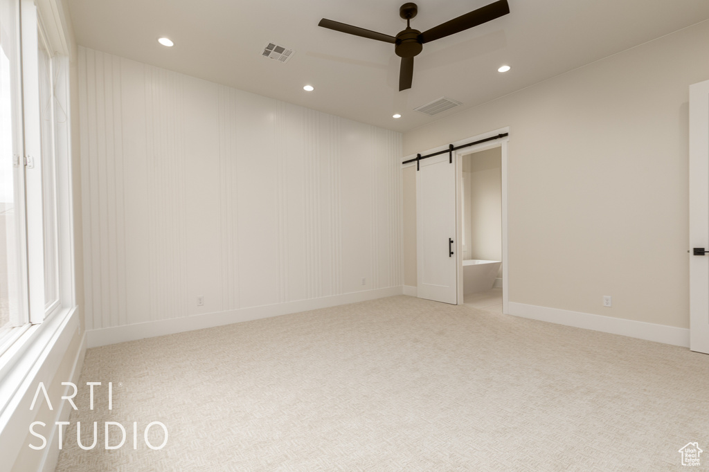 Unfurnished bedroom with carpet, recessed lighting, a barn door, ceiling fan, and baseboards