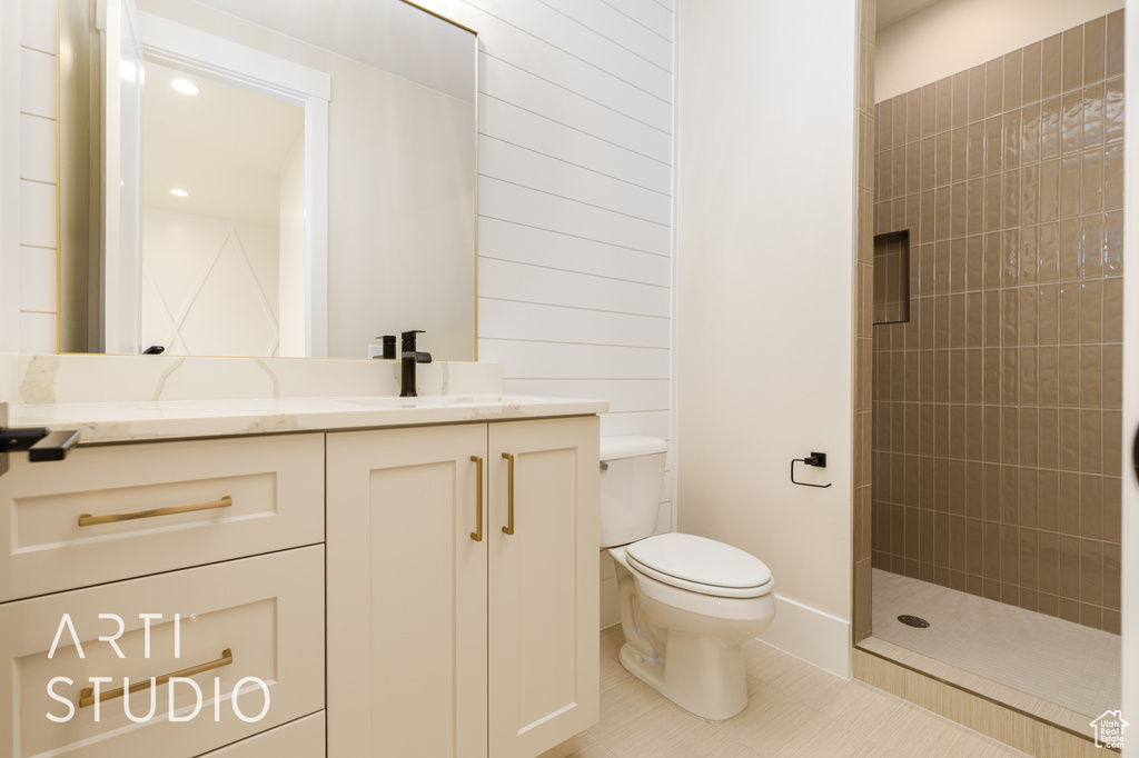 Full bath with toilet, vanity, tiled shower, and tile patterned floors