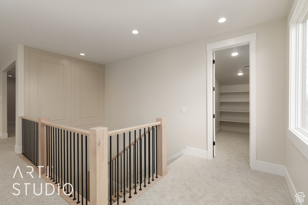 Hall with an upstairs landing, light colored carpet, recessed lighting, and baseboards