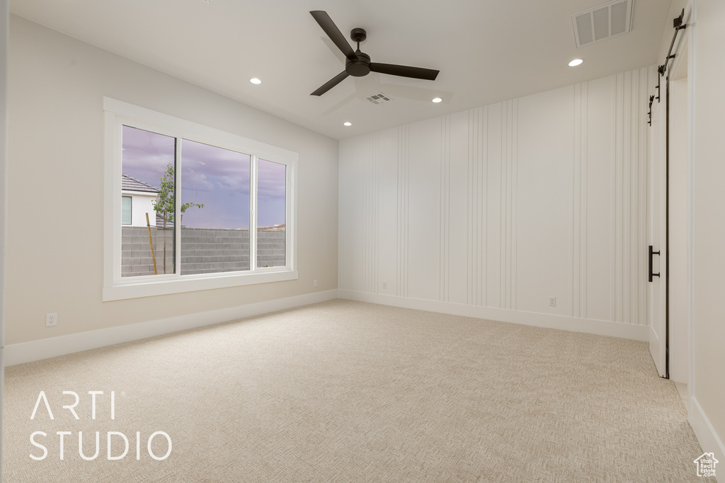 Carpeted empty room with recessed lighting, a ceiling fan, a barn door, and baseboards