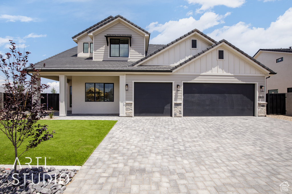 View of front of home with decorative driveway, a tile roof, an attached garage, and board and batten siding