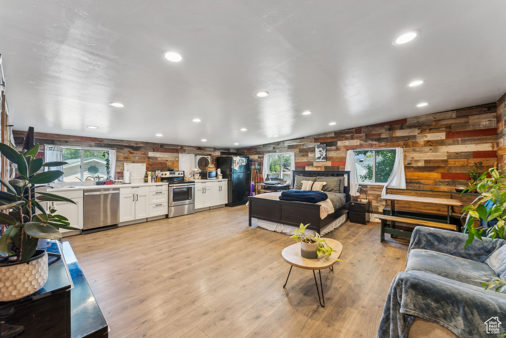 Living area with light wood-style floors, wood walls, and recessed lighting