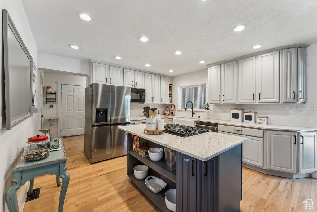 Kitchen with open shelves, stainless steel fridge, a sink, dishwashing machine, and black microwave