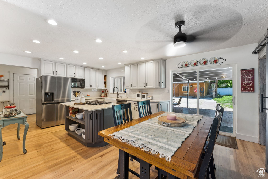 Dining area featuring a ceiling fan, light wood-style floors, recessed lighting, and a textured ceiling