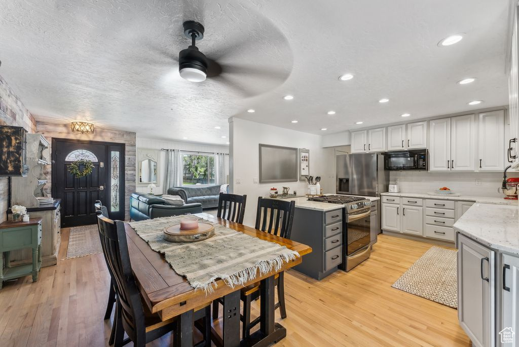 Kitchen with stainless steel appliances, white cabinetry, light wood-type flooring, a textured ceiling, and recessed lighting