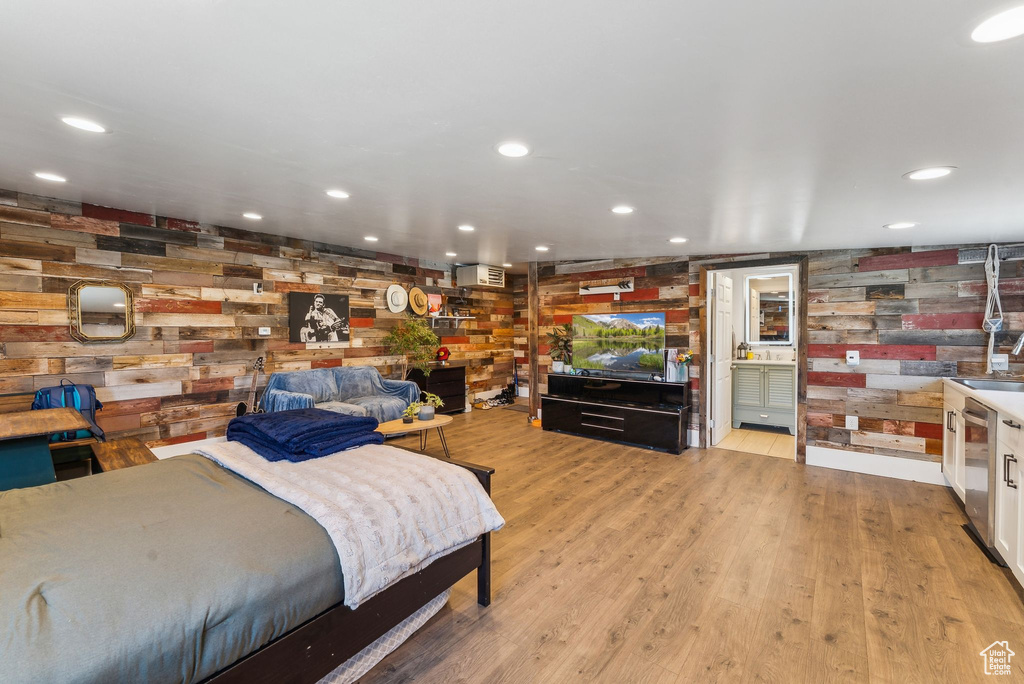 Bedroom with light wood finished floors, recessed lighting, and wood walls