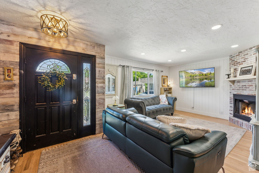 Living area featuring wood finished floors, wood walls, a textured ceiling, a fireplace, and baseboards