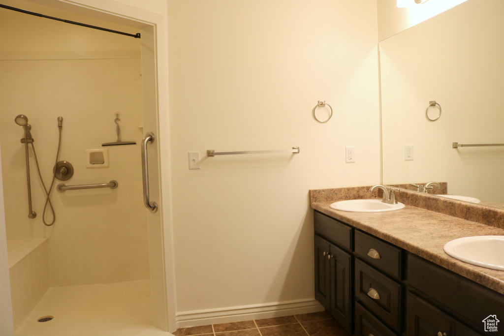 Full bath featuring double vanity, a shower, baseboards, and tile patterned floors