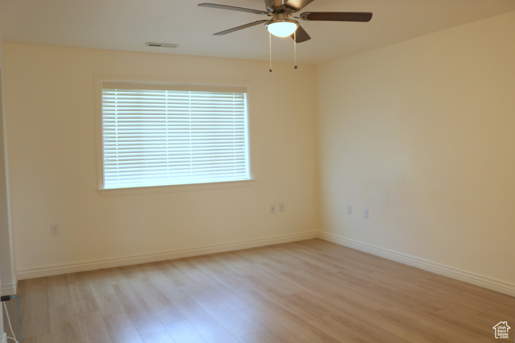Unfurnished room featuring light wood-style floors, ceiling fan, and baseboards