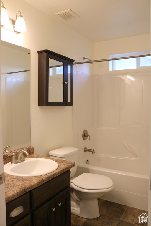 Full bath with vanity, shower / bathtub combination, toilet, and stone finish flooring