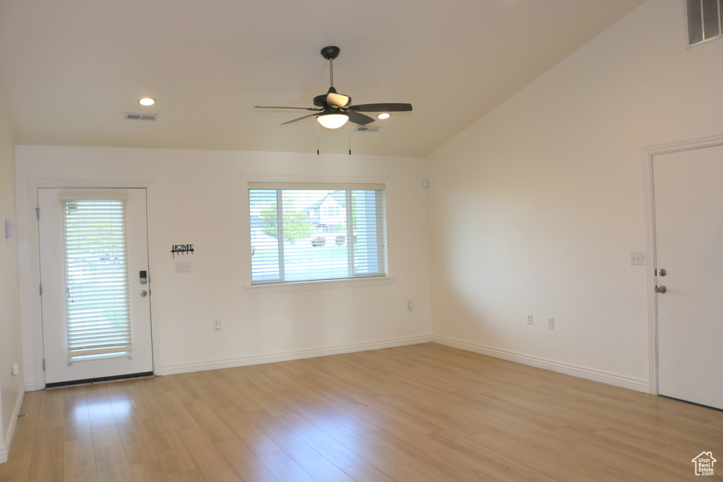 Foyer featuring ceiling fan, plenty of natural light, light wood-type flooring, vaulted ceiling, and baseboards