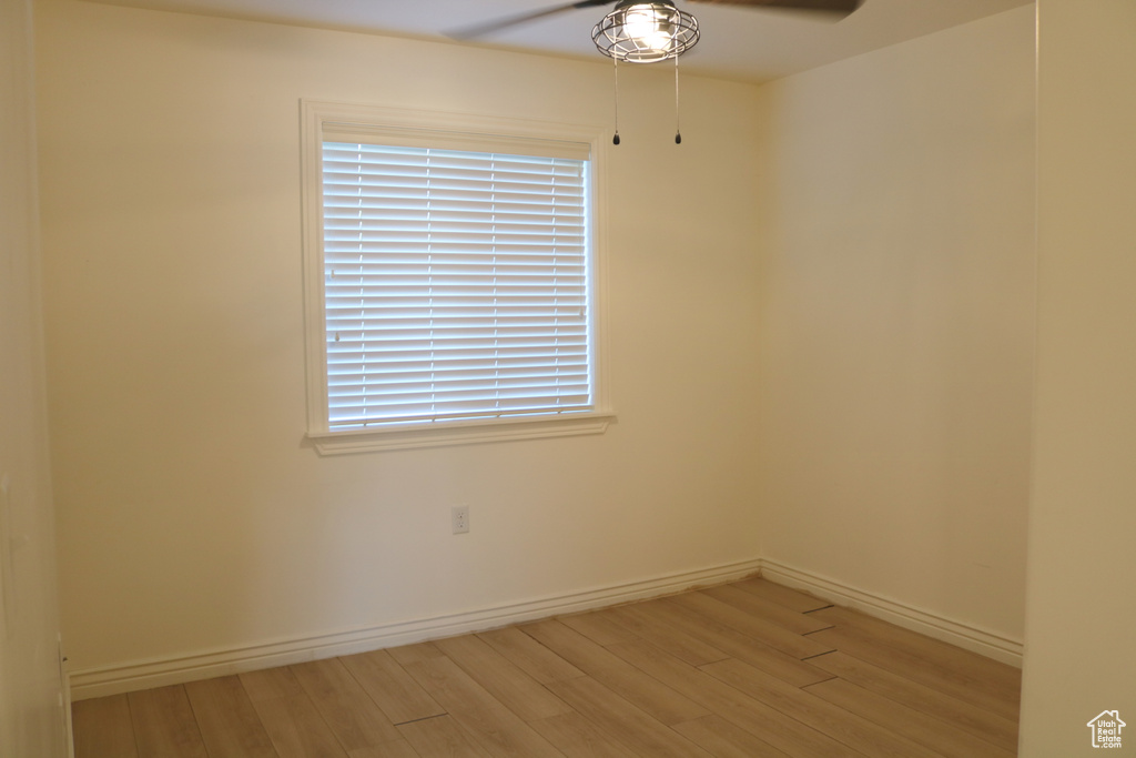Spare room featuring ceiling fan, light wood-style flooring, baseboards, and healthy amount of natural light