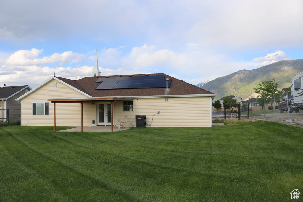 Back of property with french doors, solar panels, a patio area, a mountain view, and central air condition unit