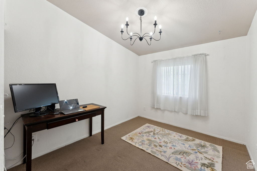 Carpeted home office featuring a chandelier, vaulted ceiling, and baseboards