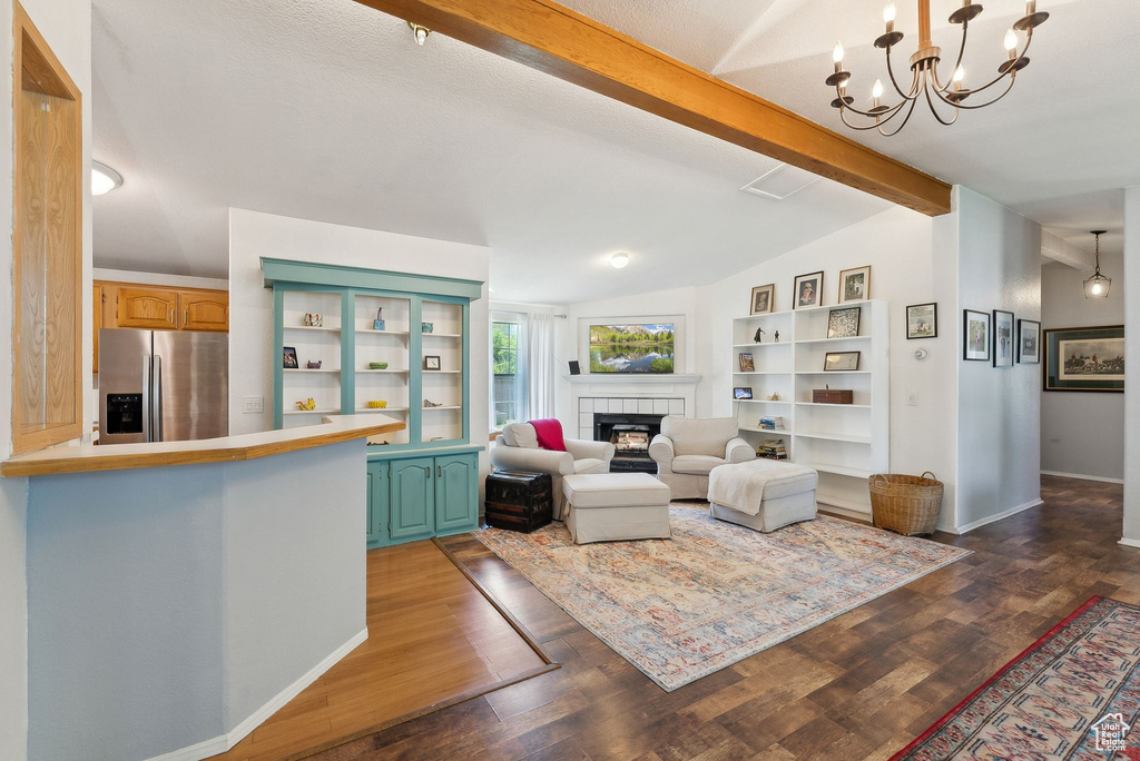 Living room with a fireplace, dark wood-style floors, baseboards, and a chandelier