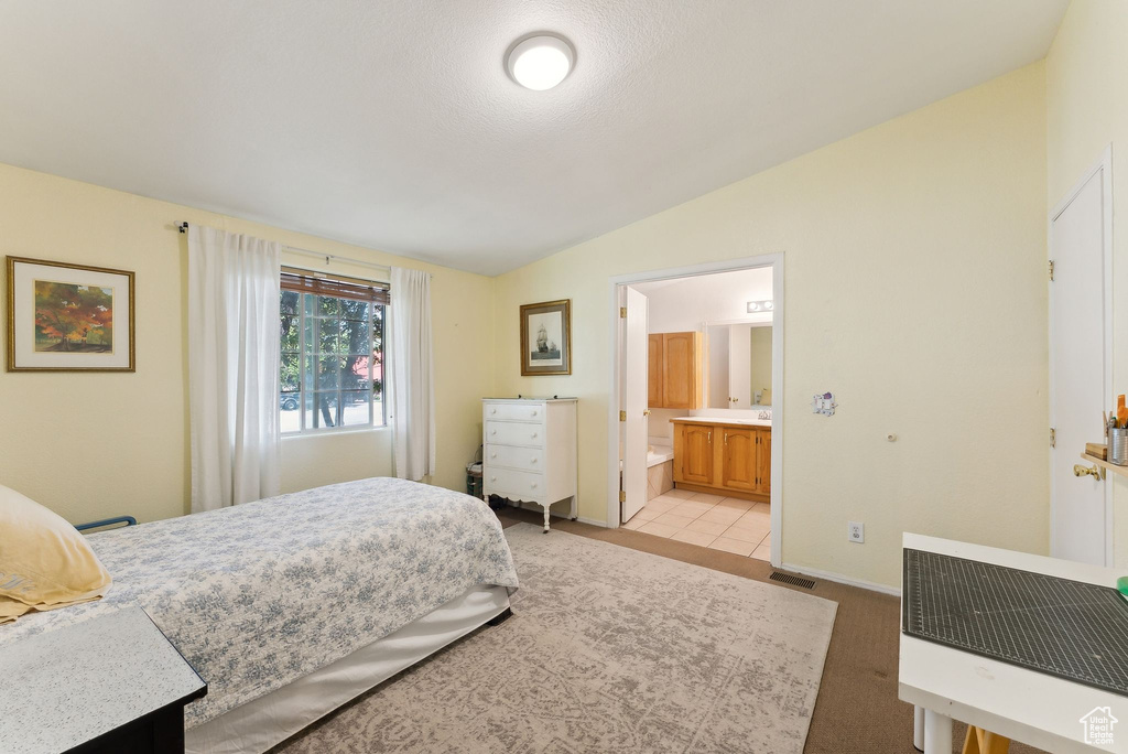Bedroom with vaulted ceiling, ensuite bath, and baseboards