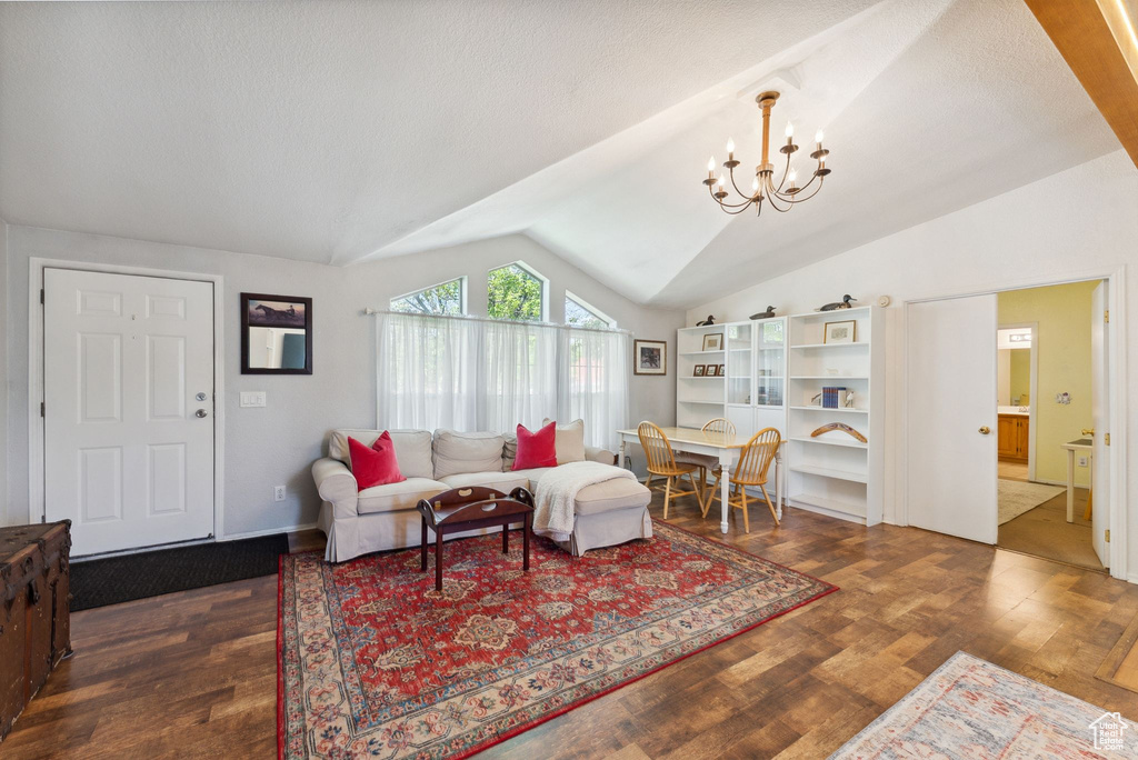Living room featuring vaulted ceiling, a chandelier, and wood finished floors