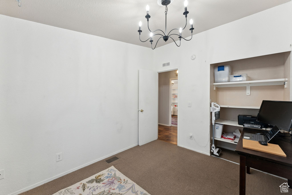 Carpeted home office featuring a chandelier and baseboards