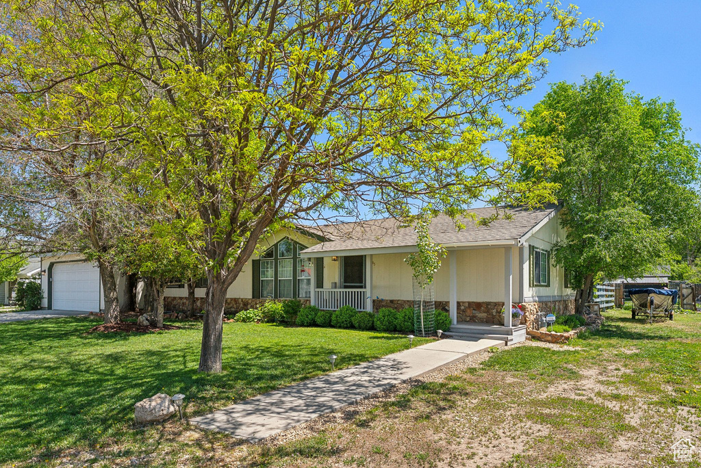 Ranch-style house featuring stone siding, a front lawn, a porch, and roof with shingles