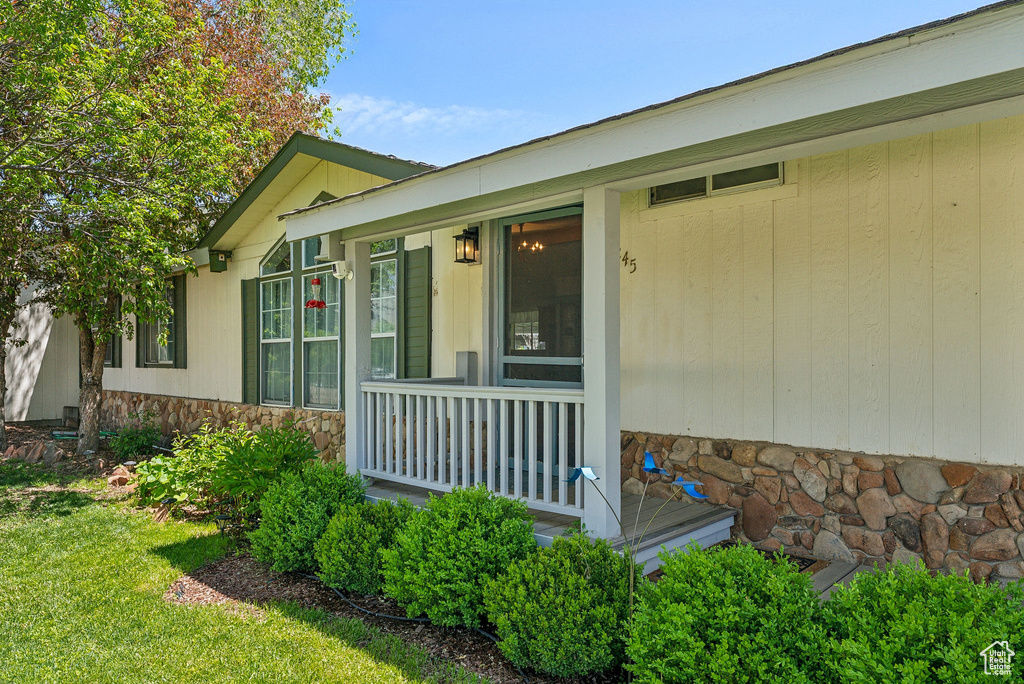 View of exterior entry with stone siding and a porch