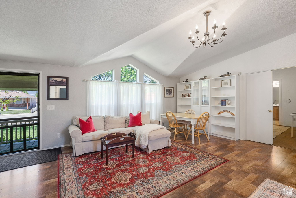 Living room with lofted ceiling, a chandelier, and wood finished floors