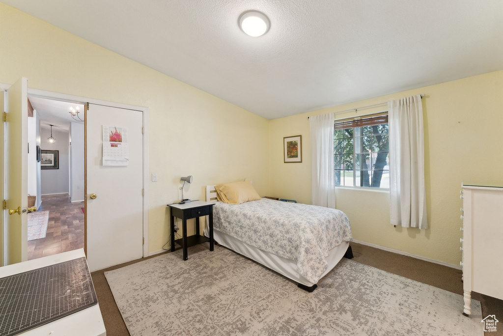 Bedroom featuring vaulted ceiling, a chandelier, and baseboards