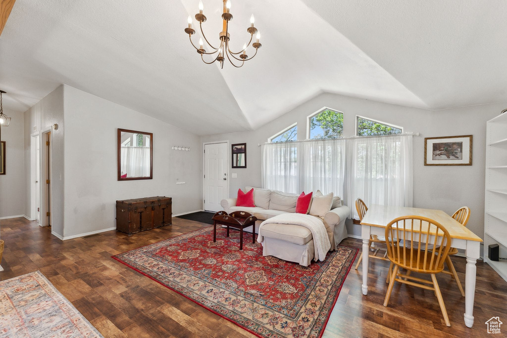 Living area with a chandelier, vaulted ceiling, wood finished floors, and baseboards