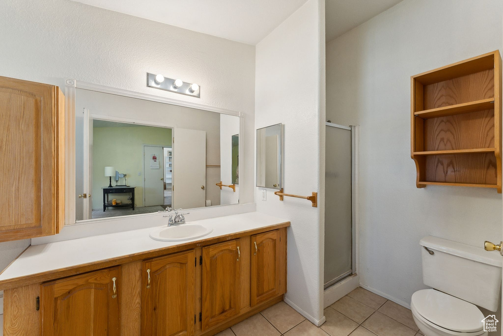 Full bath with tile patterned floors, vanity, toilet, and a shower stall