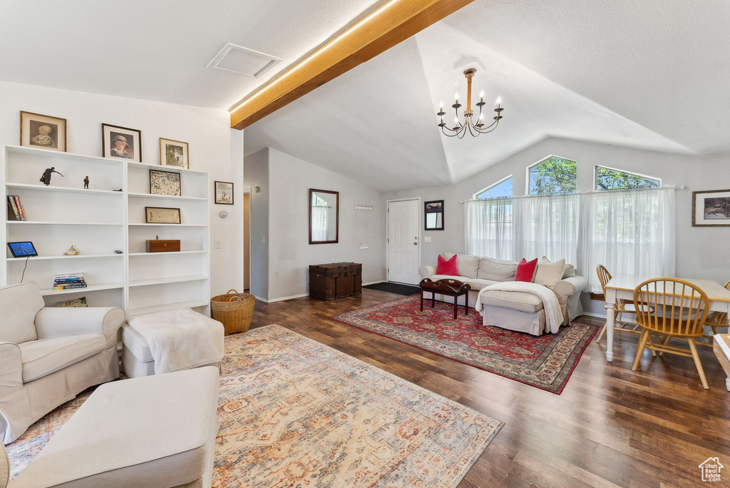 Living room with healthy amount of natural light, lofted ceiling, dark wood-type flooring, and a chandelier