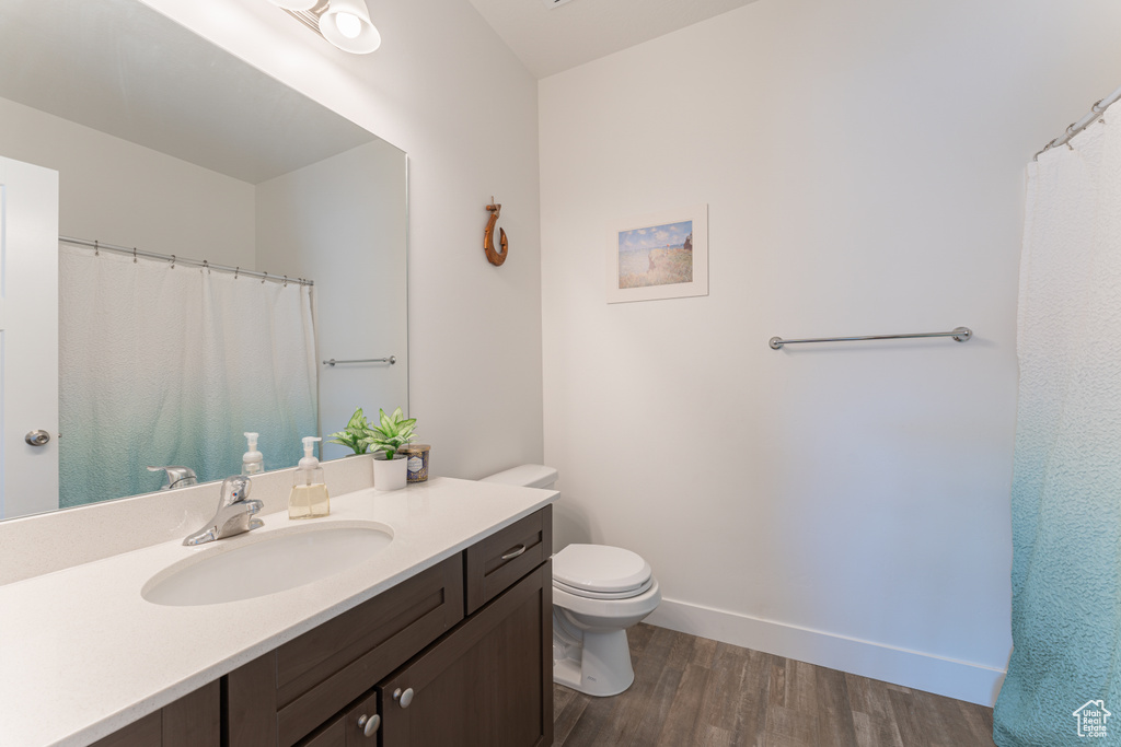 Bathroom featuring wood finished floors, toilet, vanity, and baseboards