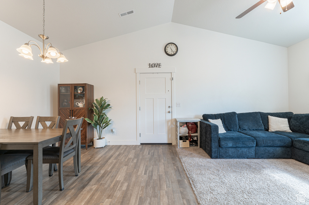 Dining space with lofted ceiling, a chandelier, light wood finished floors, and ceiling fan