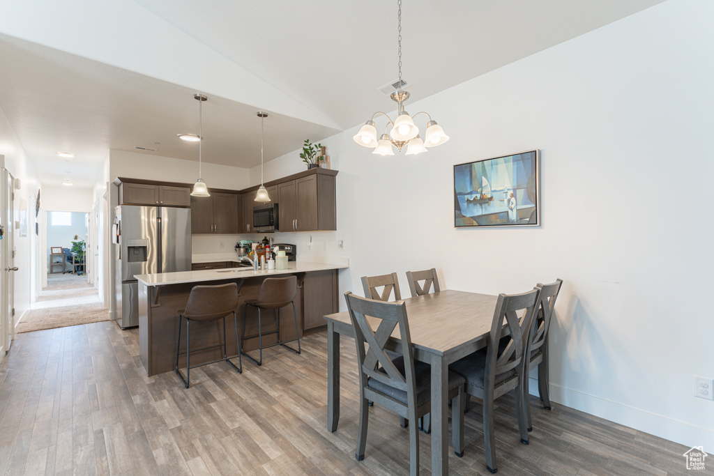 Dining room featuring light wood-style floors, a chandelier, baseboards, and lofted ceiling